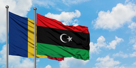 Romania and Libya flag waving in the wind against white cloudy blue sky together. Diplomacy...