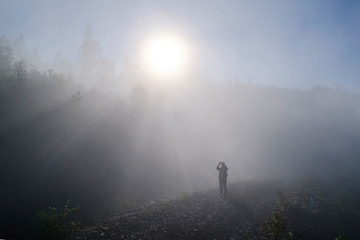 Misty landscape. Tourist taking pictures of morning fog sunrise high in the Carpathian mountains. Ukraine.
