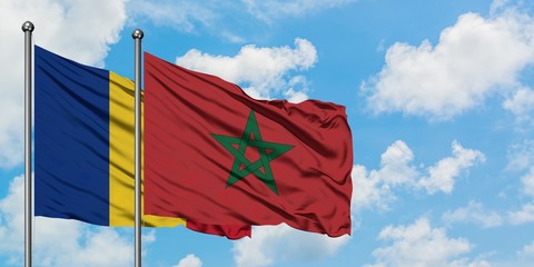 Romania and Morocco flag waving in the wind against white cloudy blue sky together. Diplomacy...