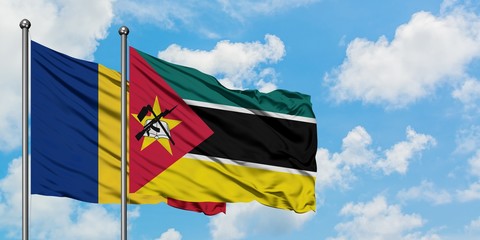 Romania and Mozambique flag waving in the wind against white cloudy blue sky together. Diplomacy...