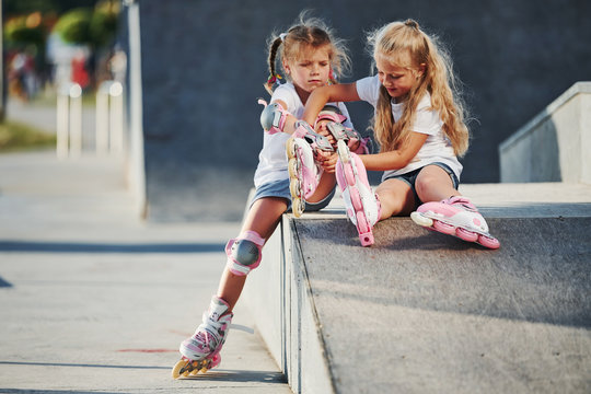 Warm weather. On the ramp for extreme sports. Two little girls with roller skates outdoors have fun
