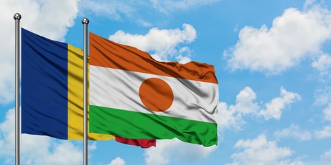 Romania and Niger flag waving in the wind against white cloudy blue sky together. Diplomacy...