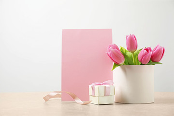 Blank greeting card, tulips and gift on table, space for text. Happy Mother's day
