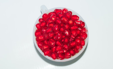 close up of fresh tasty red pomegranate seeds in a white cup