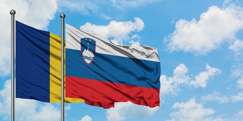 Romania and Slovenia flag waving in the wind against white cloudy blue sky together. Diplomacy concept, international relations.