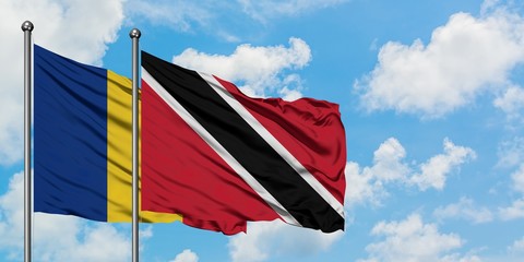 Romania and Trinidad And Tobago flag waving in the wind against white cloudy blue sky together....