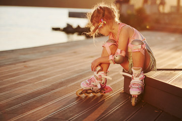 Happy cute kid with her roller skates. Unbelievable sunlight