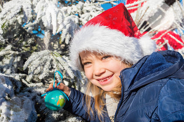 beautiful girl decorating her Christmas tree in the garden