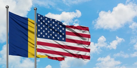 Romania and United States flag waving in the wind against white cloudy blue sky together. Diplomacy concept, international relations.