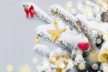 Christmas tree in snow background. New Year composition with fir tree, balls and lights and bokeh.