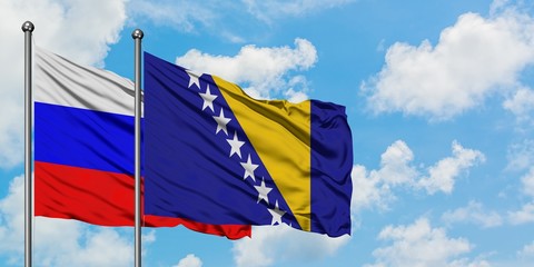 Russia and Bosnia Herzegovina flag waving in the wind against white cloudy blue sky together. Diplomacy concept, international relations.