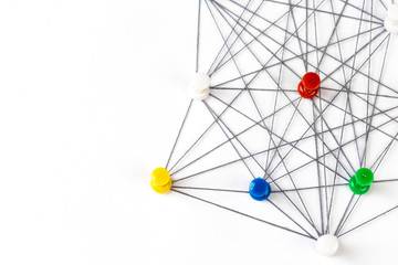 Network with colorful pins and string,  linked together with string on a white background suggesting a network of connections.