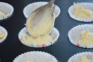 The process of making cupcakes. the dough in the tins and spoon. Cooking. Baking desserts for tea and coffee.
