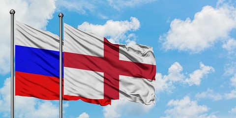 Russia and England flag waving in the wind against white cloudy blue sky together. Diplomacy concept, international relations.
