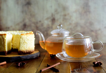 Hot green tea in a glass Cup, glass teapot with green tea and cheesecake on a wooden platter on the table