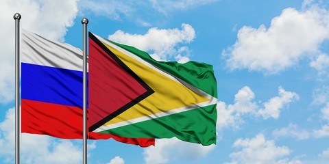 Russia and Guyana flag waving in the wind against white cloudy blue sky together. Diplomacy concept, international relations.