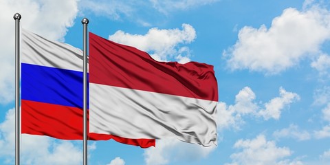 Russia and Indonesia flag waving in the wind against white cloudy blue sky together. Diplomacy concept, international relations.