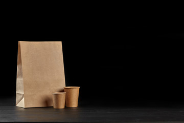 Eco friendly disposable tableware standing on dark surface against black background. Biodegradable craft dishes. Recycling concept. Close-up shot.