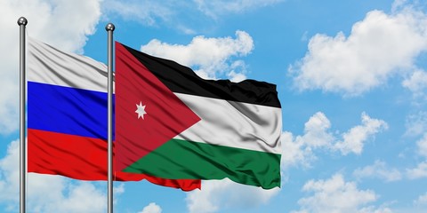 Russia and Jordan flag waving in the wind against white cloudy blue sky together. Diplomacy concept, international relations.
