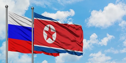 Russia and North Korea flag waving in the wind against white cloudy blue sky together. Diplomacy concept, international relations.