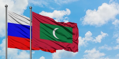 Russia and Maldives flag waving in the wind against white cloudy blue sky together. Diplomacy concept, international relations.