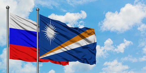 Russia and Marshall Islands flag waving in the wind against white cloudy blue sky together. Diplomacy concept, international relations.