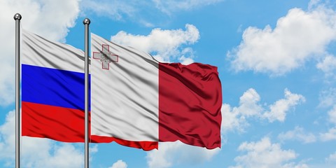 Russia and Malta flag waving in the wind against white cloudy blue sky together. Diplomacy concept, international relations.
