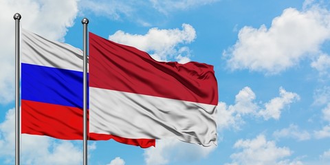 Russia and Monaco flag waving in the wind against white cloudy blue sky together. Diplomacy concept, international relations.