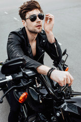 sexy man in sunglasses sitting on motorcycle and looking forward