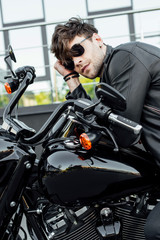 handsome young man in leather jacket resting while sitting on motorcycle