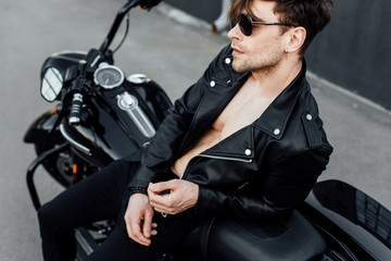 Fototapeta na wymiar handsome motorcyclist with naked torso leaning on motorcycle
