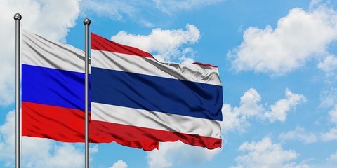 Russia and Thailand flag waving in the wind against white cloudy blue sky together. Diplomacy concept, international relations.