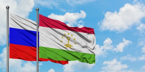 Russia and Tajikistan flag waving in the wind against white cloudy blue sky together. Diplomacy concept, international relations.