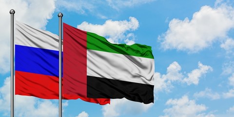 Russia and United Arab Emirates flag waving in the wind against white cloudy blue sky together. Diplomacy concept, international relations.