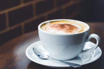 close up modern hot black coffee the cappuccino on wood background with coffee bubble foam pattern and texture in white cup looking and feel so delicious on glasses table in coffee shop.