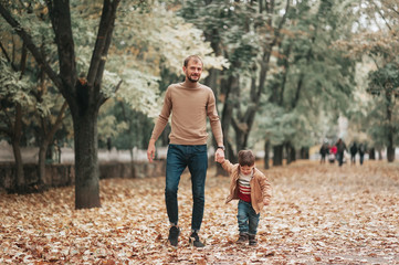 Happy father and son holding hands while walking in park. Relationship between dad and son. Social psychology. Weekend together with family. People lifestyle chilhood