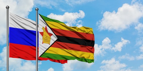 Russia and Zimbabwe flag waving in the wind against white cloudy blue sky together. Diplomacy concept, international relations.