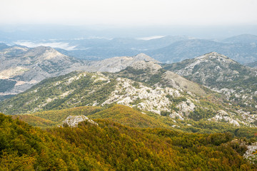 Fototapeta premium Lovcen viewpoint during fall season with low clouds hugging the trees