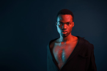 Confident and serious. Futuristic neon lighting. Young african american man in the studio