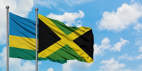 Rwanda and Jamaica flag waving in the wind against white cloudy blue sky together. Diplomacy concept, international relations.