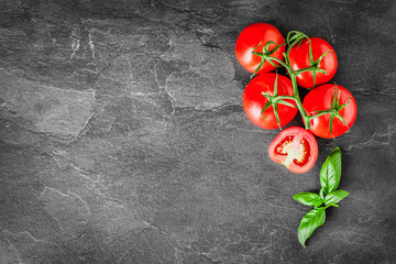 Delicious fresh tomatoes and basil on dark stone table. Ripe tomato concept with copy text space,...