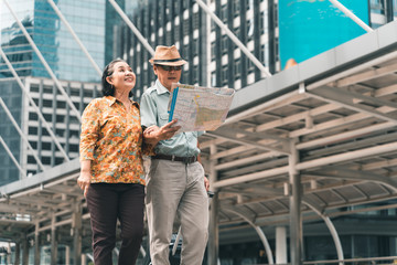 A couple of elderly Asian tourists visiting the capital happily and having fun and looking at the map to find places to visit.