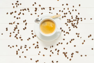 White cup with coffee and spoon on the white wooden background. Separate coffee beans. Food and drink background photo.