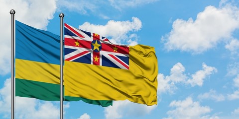 Rwanda and Niue flag waving in the wind against white cloudy blue sky together. Diplomacy concept, international relations.