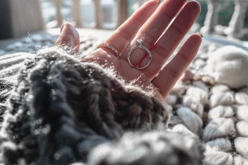 Close up of woman hand holding an elegant engagement diamond with dark gray sweater winter clothe....