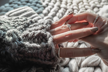  Close up of an elegant engagement diamond ring on woman finger with dark gray sweater winter...