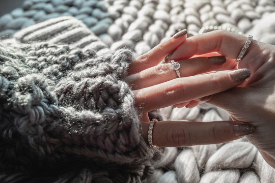  Close up of an elegant engagement diamond ring on woman finger with dark gray sweater winter clothe. love and wedding concept.soft and selective focus.