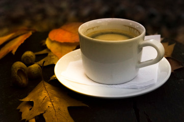 Autumn still life with a cup of coffee and fallen leaves.