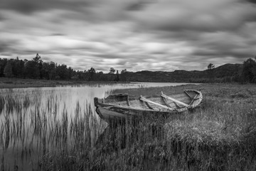 Vieux bateau de pêcheur pourri échoué sur terre dans un magnifique paysage norvégien. Prise de vue longue exposition en noir et blanc. Concept de plein air et de la nature.