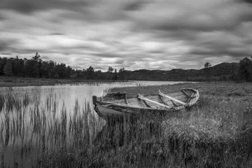 Photo sur Plexiglas Noir et blanc Vieux bateau de pêcheur pourri échoué sur terre dans un magnifique paysage norvégien. Prise de vue longue exposition en noir et blanc. Concept de plein air et de la nature.